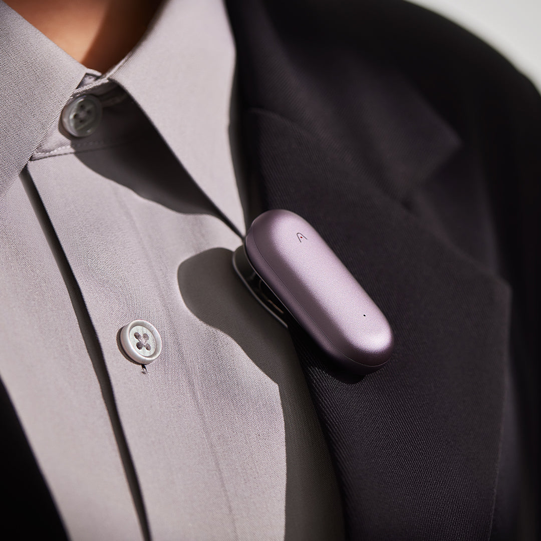 Metallic purple Plaud NotePin AI wearable device clipped to shirt, compact hands-free voice recorder for smart note-taking and transcription